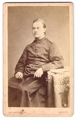 Fotografie Eug. Westendorp, Aachen, Damengraben 19, Portrait Pastor im Talar sitzend im Atelier