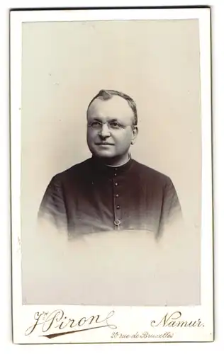 Fotografie Atelier Pirone, Namur, rue de Bruxelles 20, Portrait Priester im Talar mit Brille