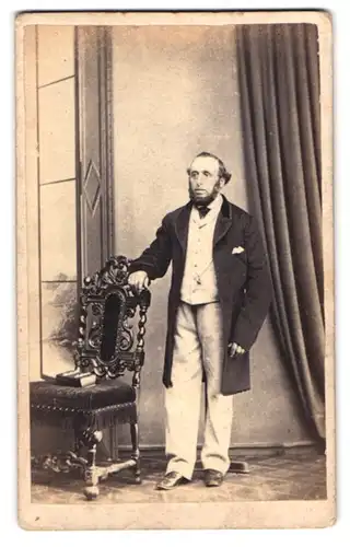 Fotografie Southgates, Southampton, Portrait älterer Herr im Anzug mit Backenbart neben einem Stuhl