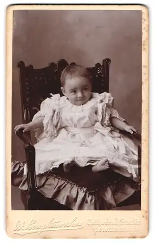 Fotografie W. Bouthton & Son, Peterborough, Portrait süsses Kleinkind im Kleid mit nackigen Füssen