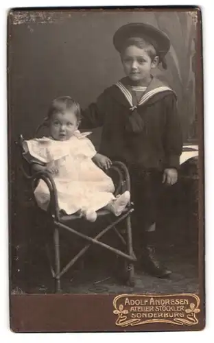 Fotografie Adolf Andresen, Sonderburg, Gr. Rathausstrasse 23, Portrait kleiner Junge im Matrosenanzug mit Kleinkind
