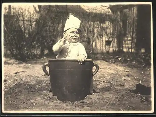 Fotografie Baby mit Zwicker & Schiffchen im Kübel