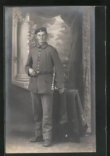 AK Soldat in Uniform am Tisch stehend, Uniformfoto