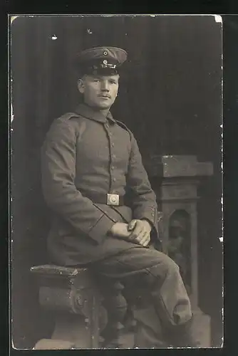 AK Soldat in Uniform auf einer Steinbank sitzend, Uniformfoto