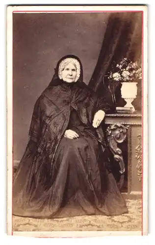 Fotografie unbekannter Fotograf und Ort, Portrait ältere Dame im dunklen Kleid mit Haube und Überwurf