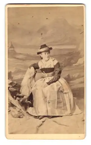 Fotografie Franz Xav. Spiegl, Miesbach, Portrait junge Frau im Trachtenkleid mit Hut vor einer Studiokulisse