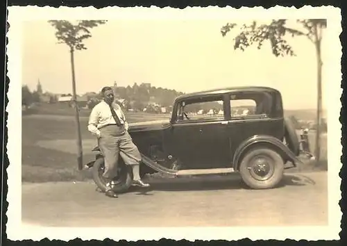 Fotografie Auto, beleibter Fahrer auf Kotflügel sitzend