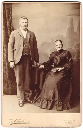 Fotografie J. Warham, Audley /Staffs., Portrait älteres Paar in hübscher Kleidung