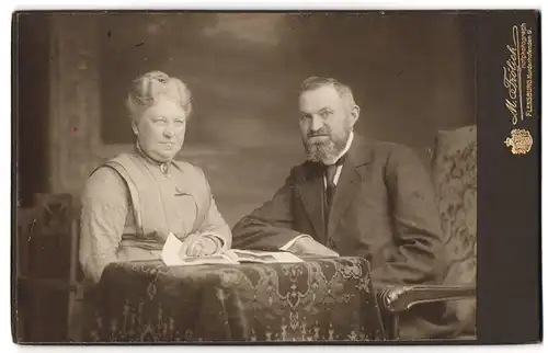 Fotografie M. Fröhlich, Flensburg, Norderhofenden 9, betagtes Paar wohl gekleidet, Dame mit Schmuck - Brosche