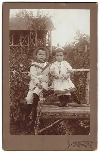 Fotografie Karl Bender, Bonbaden, Portrait zwei kleine Kinder im Matrosenanzug und Kleidchen mit Blumen in der Hand