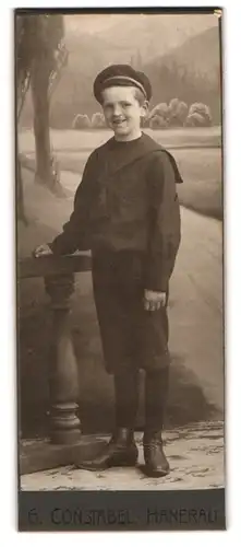 Fotografie G. Konstabel, Hanerau, lachender Knabe im Matrosenanzug vor Studiokulisse