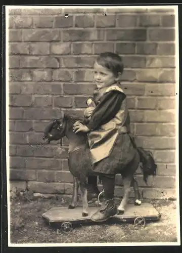 Fotografie Kleinkind auf Spielzeug-Pferd sitzend
