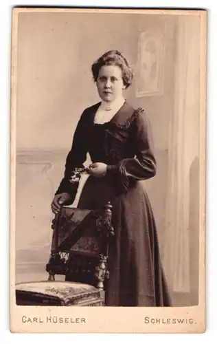 Fotografie Carl Hüseler, Schleswig, Stadtweg 147, Portrait junge Dame im Biedermeierkleid hinter einem Stuhl stehend