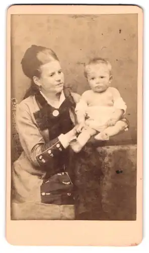Fotografie H. A. Krull, Neu-Strelitz, Portrait Mutter im Biedermeierkleid mit Kind auf dem Tisch, Mutterglück