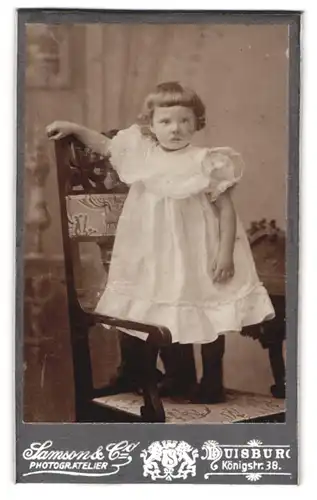 Fotografie Samson & Co., Duisburg, Königstr. 38, Portrait niedliches Mädchen im weissen Kleid mit Topfhaarschnitt