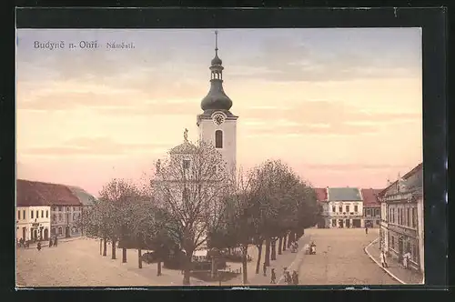 AK Budyne n. Ohri, Námesti, Hauptplatz mit Kirche im Abendlicht