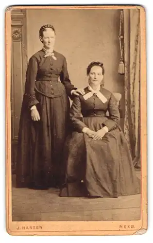 Fotografie J. Hansen, Nexö, Portrait zwei dänische Damen in Biedermeierkleidern mit Zopf und Haube