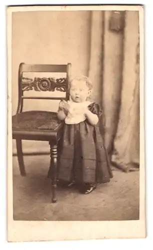 Fotografie J. Hansen, Nexö, Portrait niedliches Kleinkind im Kleid mit Sabberlatz