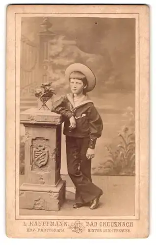 Fotografie L. Kauffmann, Bad Creuznach, hinter dem Curhaus, Portrait lässiger Knabe im Matrosenanzug mit Sommerhut