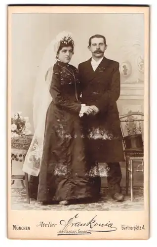 Fotografie Frankonia, München, Gärtnerplatz 4, Portrait Eheleute im schwarzen Kleid mit Schleier und Anzug