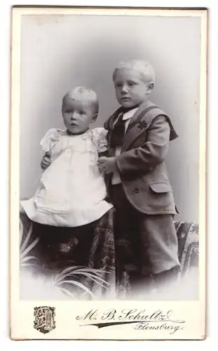 Fotografie M. B. Schultz, Flensburg, Norderhofenden 13, Grosser Bruder im Matrosenanzug hält Schwester