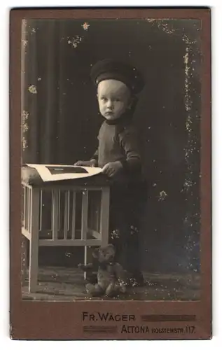 Fotografie Fr. Wäger, Altona, Holstenstr. 17, Kleiner Bursche mit Matrosenmütze und Teddy liest Bilderbuch
