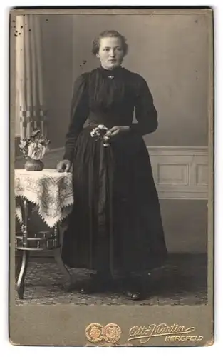 Fotografie Otto Martin, Hersfeld, Junge Frau in schwarzem Kleid lehnt an Tisch