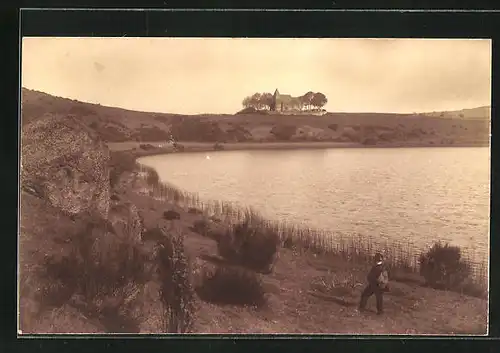 Foto-AK Weinfelder Maar (Totenmaar), Mann an Maar mit Kirche in der Ferne