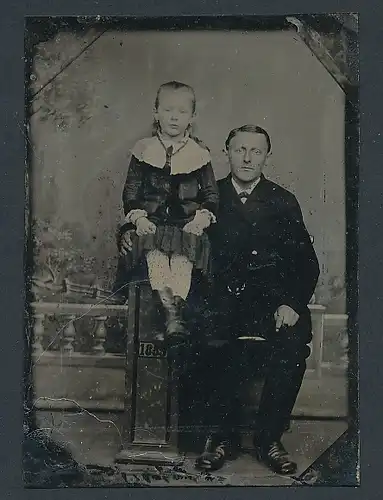 Fotografie Ferrotypie Vater im Anzug mit seiner Tochter im Biedermeierkleid auf einer Säule sitzend