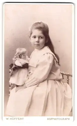 Fotografie W. Höffert, Hamburg, Esplanade 47, Portrait niedliches Mädchen im weissen Kleid mit blonder Puppe im Arm