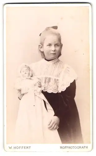 Fotografie W. Höffert, Hamburg, Esplanade 47, Portrait blondes Mädchen im Samtkleid mit Spitzenkragen, Puppe im Arm