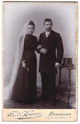 Fotografie Fritz Kayser, Hannover, Engelbostelerdamm 6, Portrait junges Paar im schwarzen Kleid und Anzug mit Zylinder