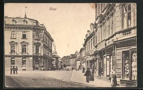 AK Most, Strassenpartie mit Geschäft Ernst Heller und Blick zur Kirche