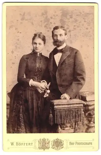 Fotografie W. Höffert, Hannover, Georgstr. 9, Portrait junges Paar im Biedermeierkleid und Anzug mit Vollbart und Fliege