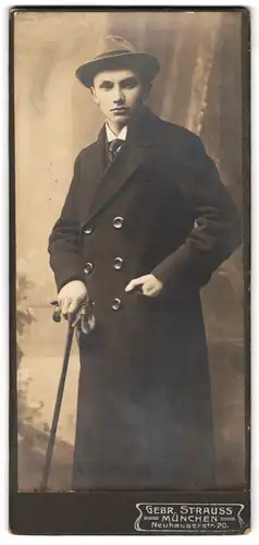 Fotografie Gebr. Strauss, München, Neuhauserstr. 20, Portrait junger Mann im dunklen Mantel mit Spazierstock und Hut