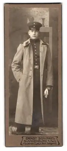 Fotografie Ernst Schinkel, Blankenburg a. Harz, Mauerstr. 3, Portrait junger Soldat in Uniform mit Mantel