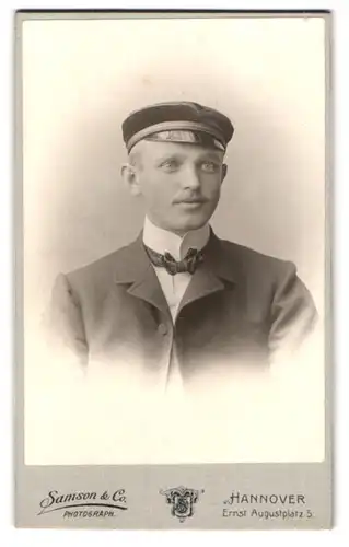 Fotografie Samson & Co., Hannover, Ernst Augustplatz 5, Portrait Student im Anzug mit Fliege und Schirmmütze