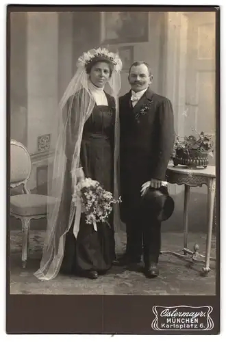 Fotografie Ostermayr, München, Karlsplatz 6, Portrait Ehepaar im schwarzen Hochzeitskleid und Anzug mit Zylinder