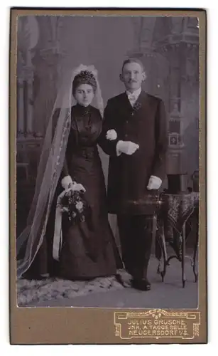 Fotografie Julius Grusche, Neugersdorf i. S., Portrait Eheleute im schwarzen Brautkleid und Anzug mit Zylinder