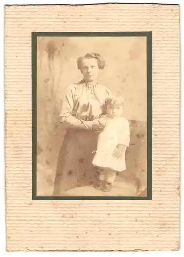 Fotografie unbekannter Fotograf und Ort, Portrait junge Mutter in seidener Bluse mit Tochter im Atelier, Mutterglück
