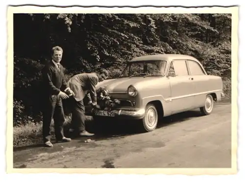 2 Fotografien Auto Ford Taunus, Männer schmücken PKW mit Blumen