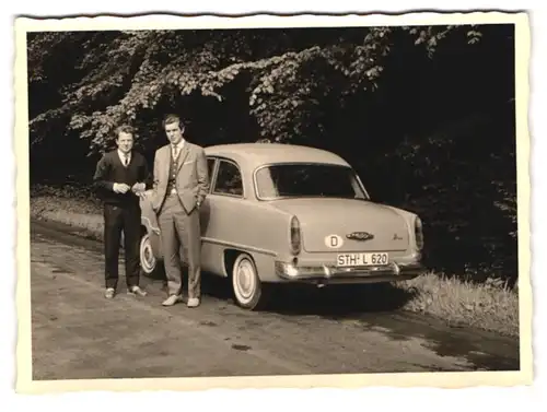 2 Fotografien Auto Ford Taunus, Männer schmücken PKW mit Blumen
