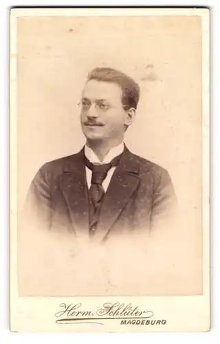 Fotografie Herm. Schlüter, Magdeburg, Breite Weg 165, Portrait charmanter junger Mann mit Brille und Schnurrbart