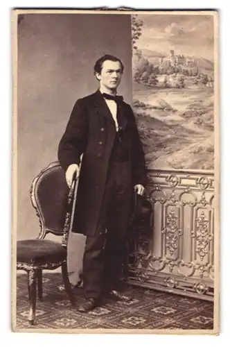 Fotografie unbekannter Fotograf und Ort, Portrait junger Mann im dunklen Anzug vor einer Studiokulisse, 1863