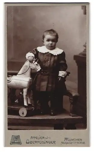 Fotografie Oberpollinger, München, Neuhauser-Str. 44-46, Portrait kleines Kind im Kleidchen mit Holzpferd auf Rädern