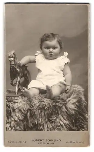 Fotografie Hubert Schilling, Fürth i. B., Karolinenstr. 14, Portrait pummeliges Kind im weissen Kleidchen mit Holzpferd