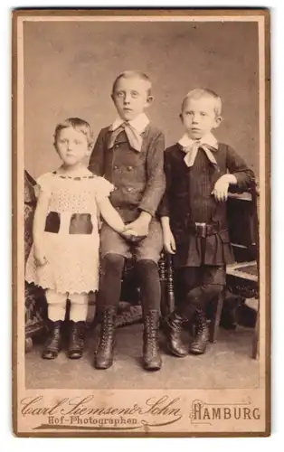 Fotografie Carl Siemsen & Sohn, Hamburg-St. Georg, Steindamm 52, Portrait zwei Jungen und Mädchenin modischer Kleidung