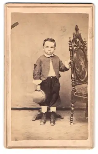 Fotografie unbekannter Fotograf und Ort, Portrait kleiner Knabe in kurzen Hosen und Bolero mit Hut in der Hand