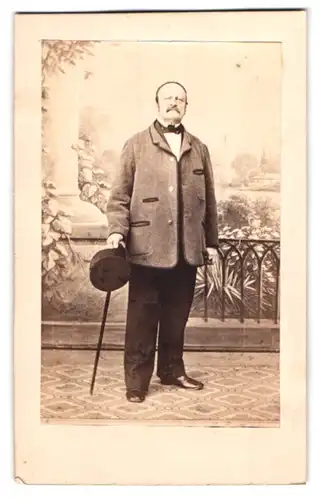 Fotografie unbekannter Fotograf und Ort, Portrait rundlicher Herr im Anzug mit Hut und Stock