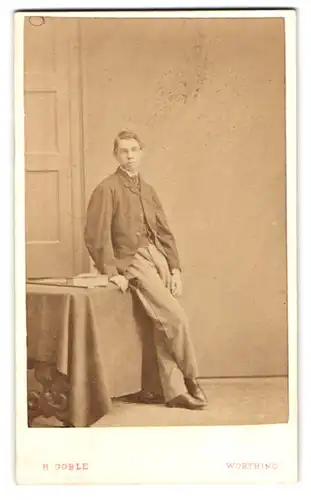 Fotografie H. Goble, Worthing, Portrait junger Mann im Anzug lehnt auf einem Tisch, 1865